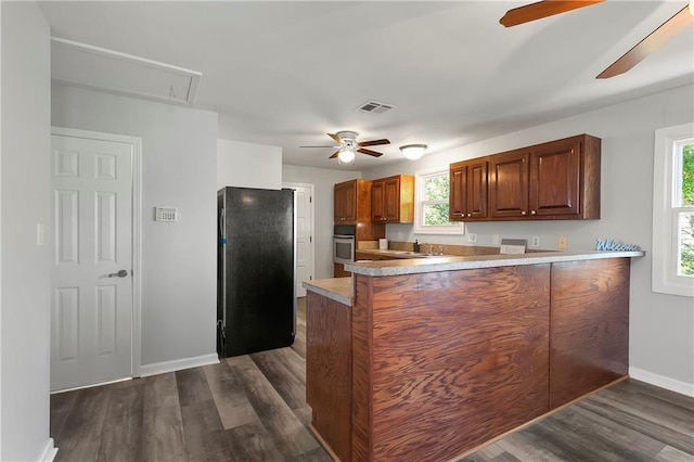 kitchen featuring oven, dark wood-style floors, visible vents, freestanding refrigerator, and a ceiling fan