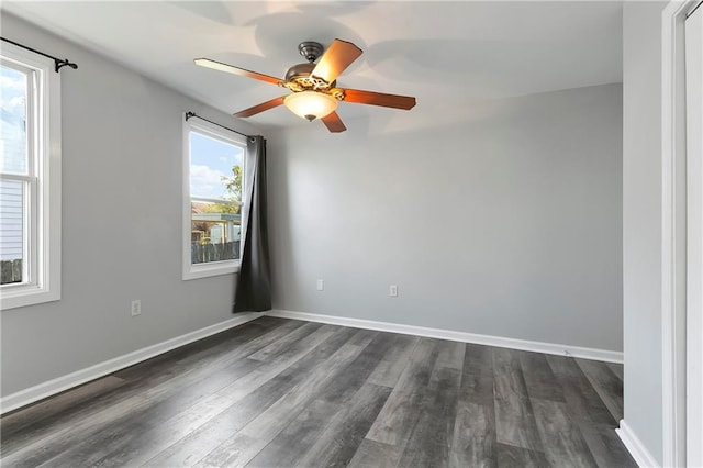 spare room featuring baseboards, ceiling fan, and dark wood finished floors