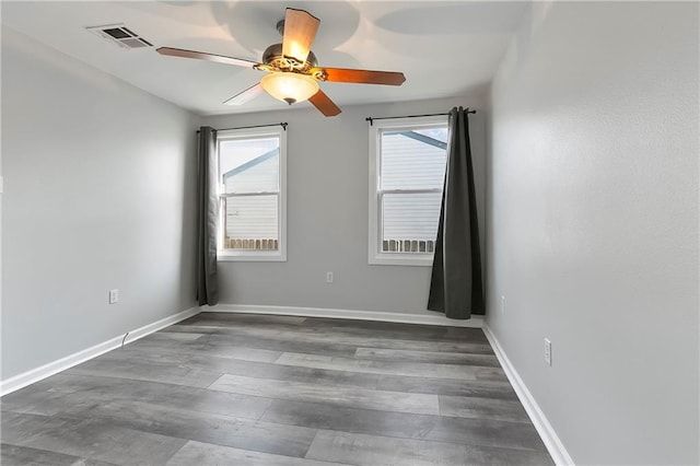 empty room featuring wood finished floors, baseboards, ceiling fan, and visible vents