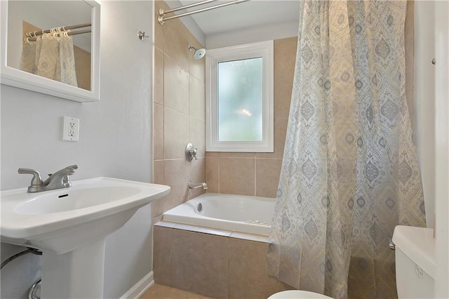 full bath featuring toilet, tiled shower / bath combo, and a sink