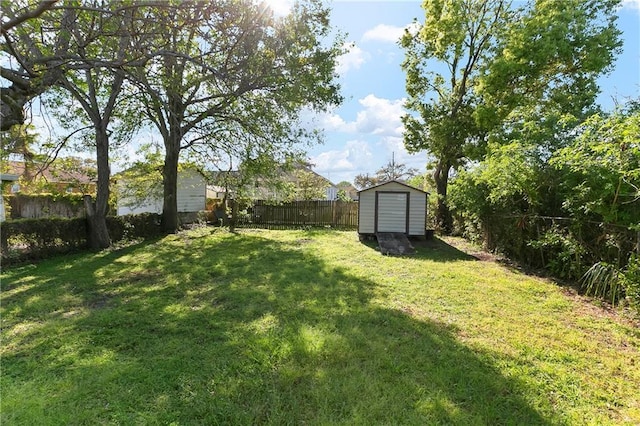 view of yard with an outdoor structure, a fenced backyard, and a storage shed