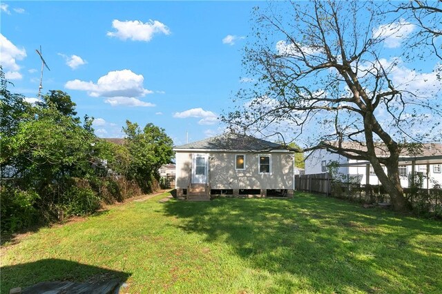 back of property with a lawn, fence, and entry steps