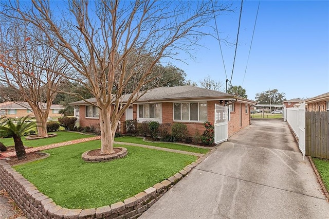 view of front of home with brick siding, driveway, fence, and a front lawn