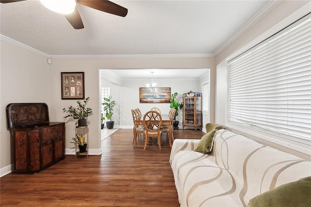 living room with crown molding, baseboards, wood finished floors, and ceiling fan with notable chandelier