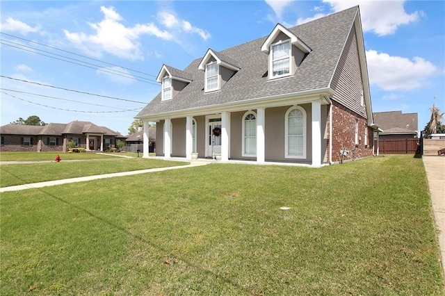 cape cod home featuring brick siding, fence, a front lawn, and roof with shingles