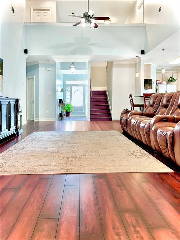 living area featuring ceiling fan, wood finished floors, and a towering ceiling