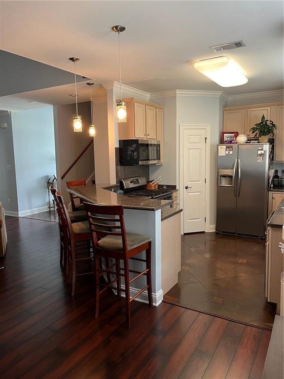 kitchen featuring crown molding, dark wood-type flooring, visible vents, a peninsula, and appliances with stainless steel finishes