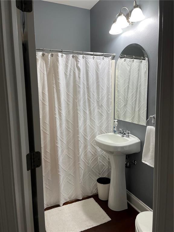full bath with baseboards, toilet, and a shower with shower curtain