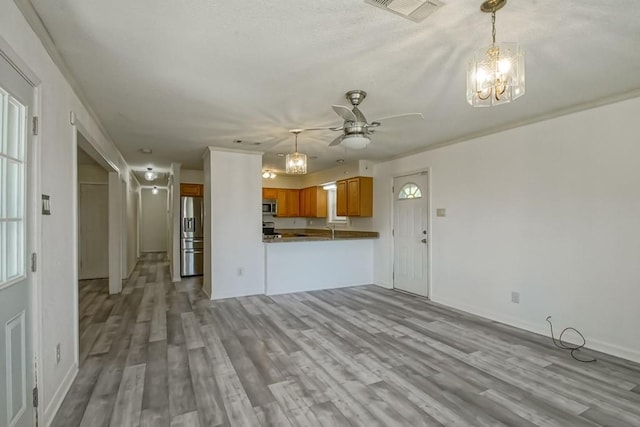 7984 Edgelake Ct, New Orleans, LA 70126 - unfurnished living room with baseboards, light wood-style flooring, visible vents, ceiling fan with notable chandelier, and a sink