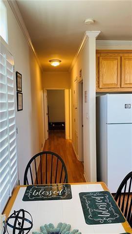 2433 Perdido St, New Orleans, LA 70119 - kitchen with freestanding refrigerator, crown molding, wood finished floors, and brown cabinetry