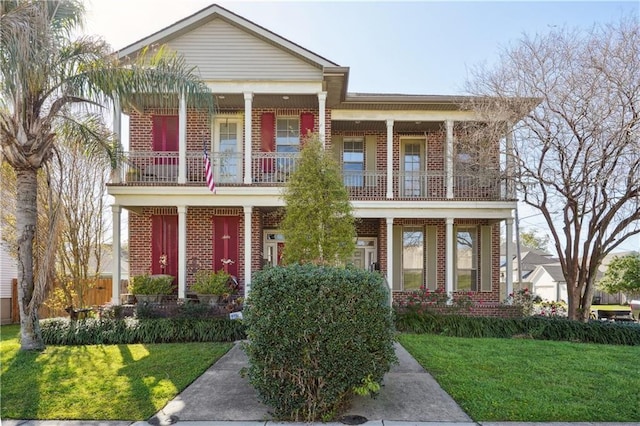 view of front of home featuring a balcony, a front yard, and brick siding