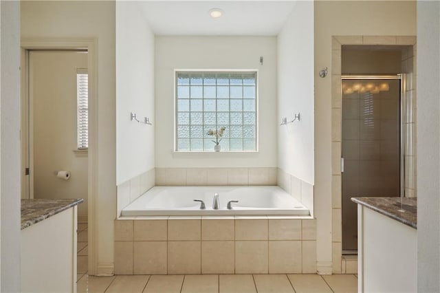 full bath featuring tile patterned floors, vanity, a stall shower, and a garden tub