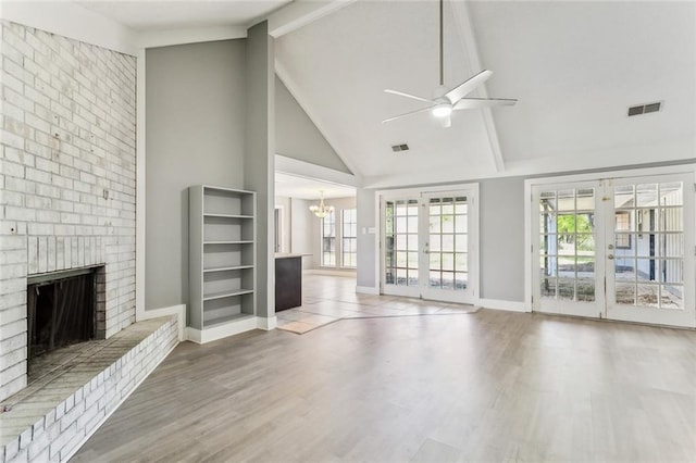 238 Blue Crane 1 Dr, Slidell, LA 70461 - unfurnished living room featuring french doors, wood finished floors, a brick fireplace, ceiling fan with notable chandelier, and visible vents