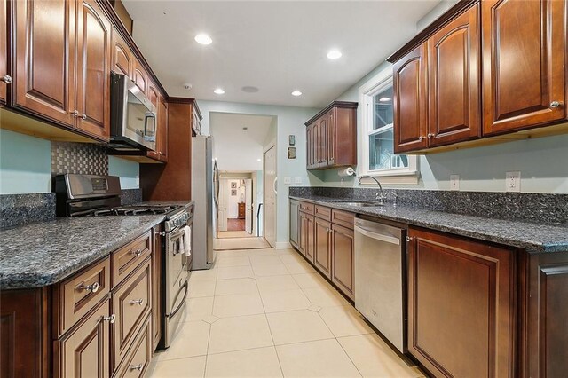 107 Stella St, Metairie, LA 70005 - kitchen with appliances with stainless steel finishes, a sink, recessed lighting, light tile patterned floors, and dark stone countertops
