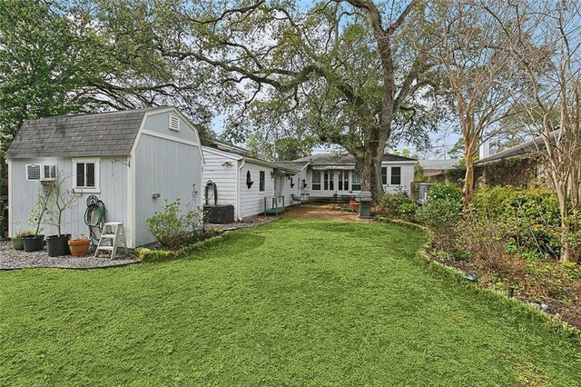 107 Stella St, Metairie, LA 70005 - rear view of property with a gambrel roof, a shed, a lawn, an outbuilding, and roof with shingles