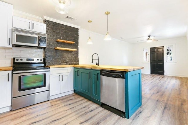 902931 Hickory St, New Orleans, LA 70118 - kitchen with wooden counters, appliances with stainless steel finishes, a sink, a peninsula, and crown molding
