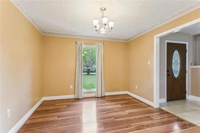803 Lake Dcote Ct, Slidell, LA 70461 - spare room featuring a chandelier, light wood finished floors, a textured ceiling, ornamental molding, and baseboards