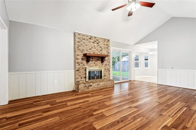 803 Lake Dcote Ct, Slidell, LA 70461 - unfurnished living room with wood finished floors, a ceiling fan, wainscoting, a brick fireplace, and a chandelier