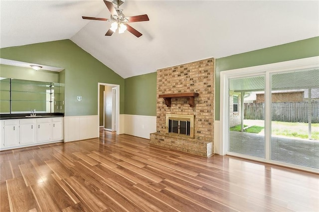 803 Lake Dcote Ct, Slidell, LA 70461 - unfurnished living room with a wainscoted wall, wood finished floors, a ceiling fan, a sink, and a fireplace