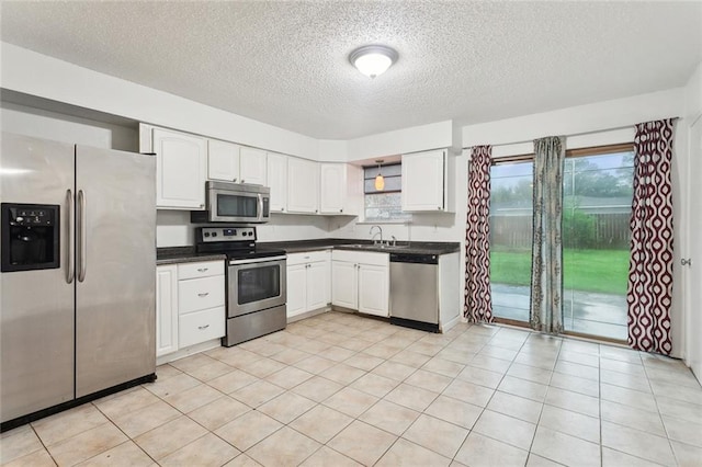 1465 Sunset Dr, Slidell, LA 70460 - kitchen with appliances with stainless steel finishes, a sink, dark countertops, a textured ceiling, and white cabinetry