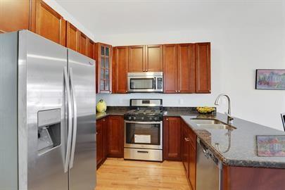 kitchen with light wood-type flooring, dark stone countertops, a sink, a peninsula, and appliances with stainless steel finishes