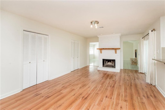17168 E Little Italy Rd, Hammond, LA 70403 - unfurnished living room with a brick fireplace, visible vents, baseboards, and light wood-type flooring