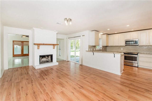 17168 E Little Italy Rd, Hammond, LA 70403 - kitchen featuring decorative backsplash, open floor plan, light wood-type flooring, and appliances with stainless steel finishes
