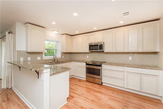 17168 E Little Italy Rd, Hammond, LA 70403 - kitchen featuring a sink, light wood finished floors, appliances with stainless steel finishes, a peninsula, and visible vents