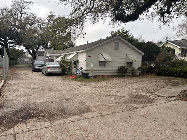 view of home's exterior featuring dirt driveway and fence