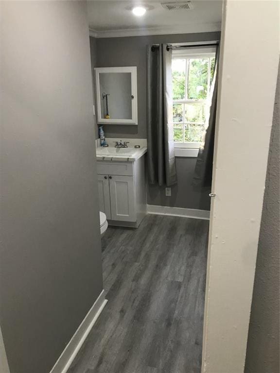 bathroom with vanity, ornamental molding, baseboards, and wood finished floors