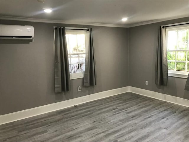 unfurnished room featuring a wall unit AC, recessed lighting, ornamental molding, baseboards, and wood finished floors
