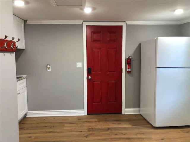 kitchen featuring freestanding refrigerator, baseboards, white cabinets, light wood-style floors, and ornamental molding