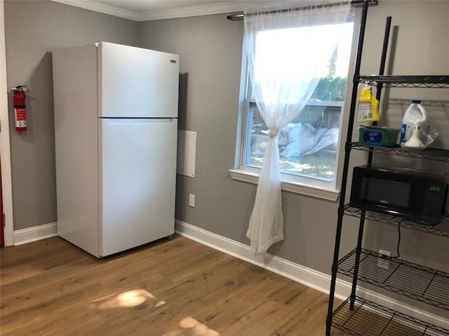 kitchen featuring black microwave, baseboards, wood finished floors, and freestanding refrigerator