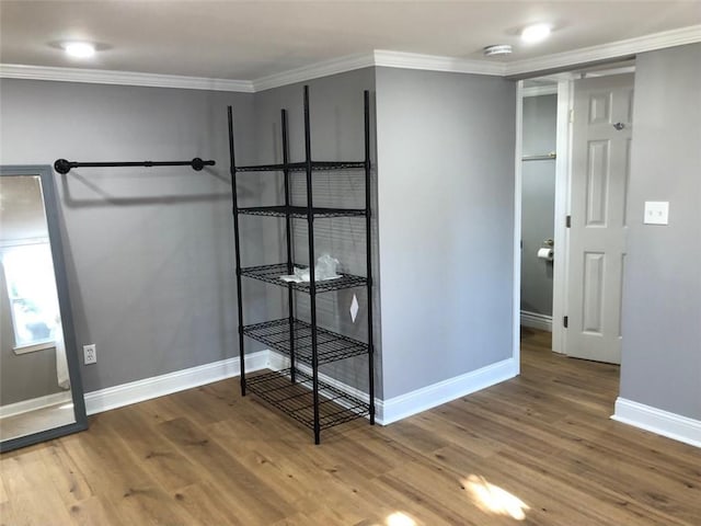 interior space with baseboards, ornamental molding, and wood finished floors