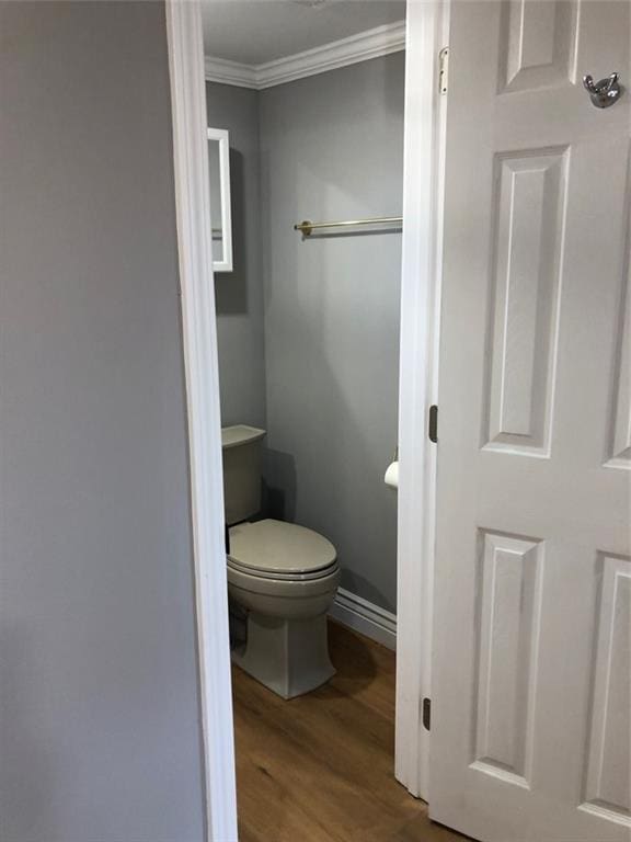 bathroom featuring toilet, wood finished floors, and ornamental molding