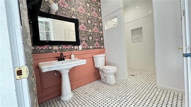 bathroom with a wainscoted wall, wallpapered walls, toilet, and a walk in shower