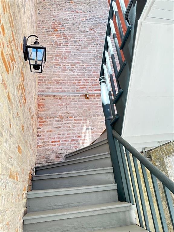 stairway featuring brick wall