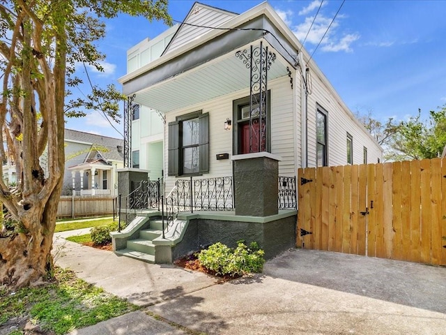 view of front of house featuring fence, a gate, and a porch