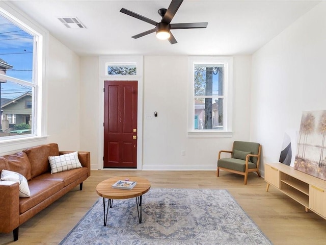 living room with visible vents, ceiling fan, light wood-type flooring, and a healthy amount of sunlight
