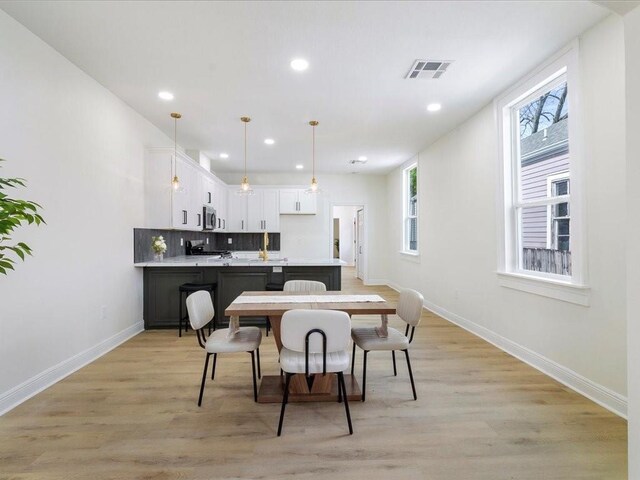 dining space with baseboards, visible vents, and light wood-type flooring