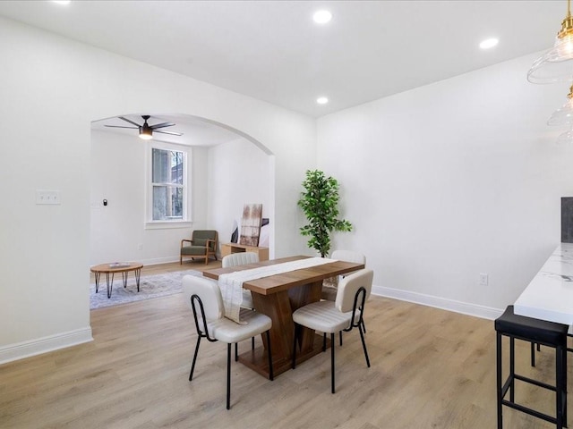 dining space with baseboards, recessed lighting, a ceiling fan, arched walkways, and light wood-style floors