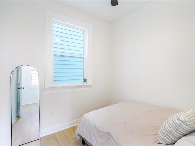bedroom with light wood finished floors, baseboards, and a ceiling fan