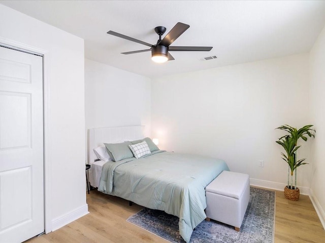 bedroom featuring baseboards, light wood-type flooring, visible vents, and a ceiling fan