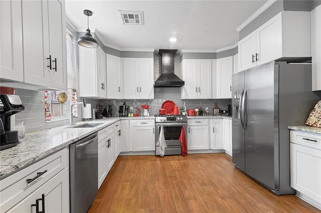 kitchen featuring stainless steel appliances, a sink, visible vents, white cabinetry, and wall chimney range hood