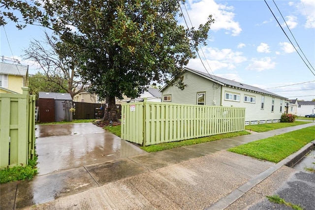 view of side of property featuring a gate, fence, a yard, and driveway
