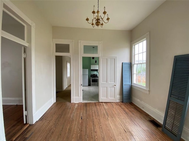 3321 Baronne St, New Orleans, LA 70113 - unfurnished bedroom with baseboards, an inviting chandelier, hardwood / wood-style flooring, and freestanding refrigerator