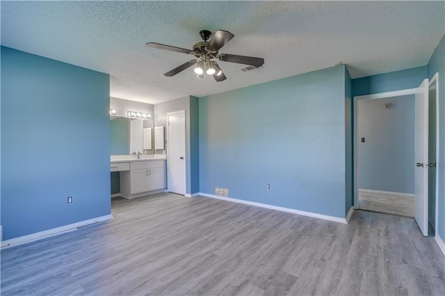 2260 Killington Dr, Harvey, LA 70058 - unfurnished bedroom with connected bathroom, baseboards, light wood-type flooring, and a textured ceiling