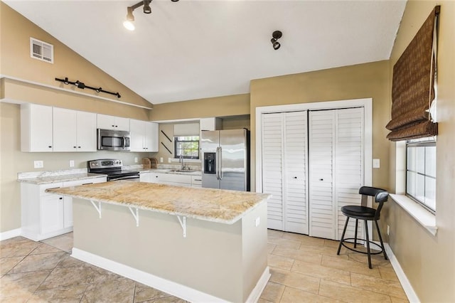230 Evella Dr, Slidell, LA 70458 - kitchen featuring appliances with stainless steel finishes, a sink, a center island, white cabinetry, and light stone countertops