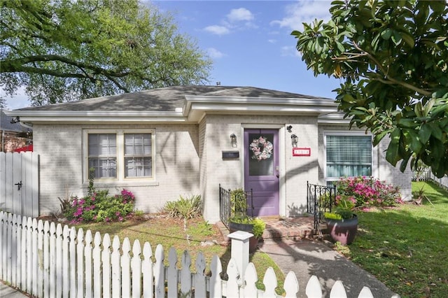 3701 Marigny St, New Orleans, LA 70122 - view of front of home with brick siding, a front yard, a fenced front yard, and roof with shingles