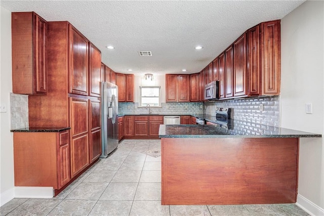 128 Belle Grove Dr, La Place, LA 70068 - kitchen with decorative backsplash, a sink, light tile patterned flooring, a peninsula, and appliances with stainless steel finishes